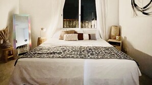 A bedroom with a bed, curtains, a bedside table, a lamp, a wall art piece, and a rug. - House at the Historical Arcos de Oaxaca (Oaxaca De Juarez)