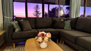 Un salon moderne avec un canapé d’angle, une table basse en bois et un vase de fleurs.