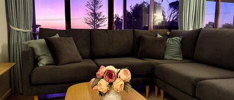 A modern living room with a sectional sofa, a wooden coffee table, and a vase of flowers.