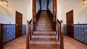 Un escalier en bois, doté d’une rampe, mène à un palier d’où l’on a vue sur un couloir.