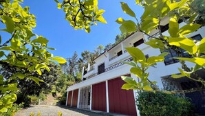 Un bâtiment à deux étages avec une porte de garage rouge, entouré de verdure et sous un ciel bleu clair.