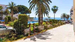 Ein Küstenhotel mit Pool, Palmen und freiem Blick auf das Meer.