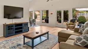 Un salon comprenant un téléviseur, une table basse, un canapé et un coin repas avec des chaises.