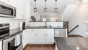 A modern kitchen with white cabinets, stainless steel appliances, and a black countertop.