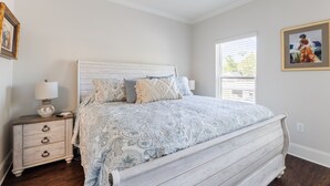 A bedroom with a bed, nightstand, lamp, and framed artwork on the wall.