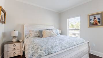 A bedroom with a bed, nightstand, lamp, and framed artwork on the wall.