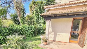 A traditional building with a tiled roof, a covered patio, and a glass door. - Sa Chessa House Two-room apartment in San Teodoro (San Teodoro)