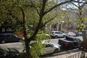 A parking lot with several cars and a truck, surrounded by trees and buildings. - 1 Bedroom Apartment in Brooklyn (Brooklyn)