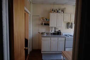 A kitchen with white cabinets, a stove, and various kitchen items on the counter. - 1 Bedroom Apartment in Brooklyn (Brooklyn)