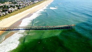Vista aérea de un pueblo costero con un muelle largo que se adentra en el océano.