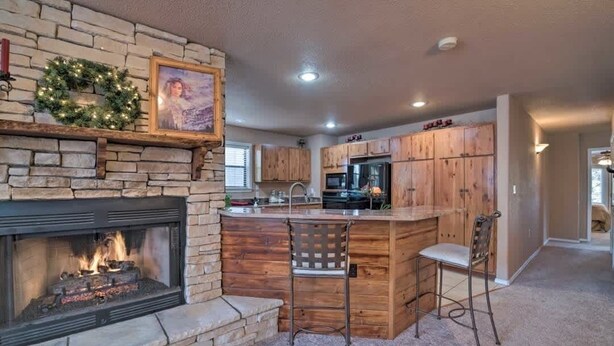 A kitchen with a stone fireplace, wooden cabinets, and a bar area.