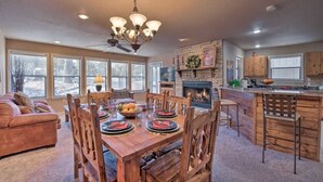 A spacious living area with a fireplace, dining table, and a kitchen area with wooden cabinets.