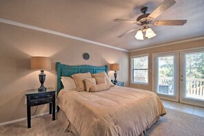 Un dormitorio con cama, dos mesitas de noche, ventilador de techo y vistas al exterior.