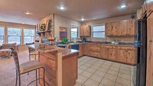 A spacious kitchen with wooden cabinets, a central island, and a dining area with chairs.