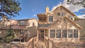 A stone house with a wooden deck and a staircase leading to the entrance.