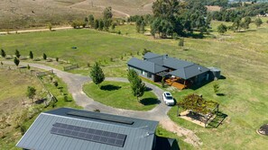 A modern house with a large garage, surrounded by a fenced property with a gravel driveway.