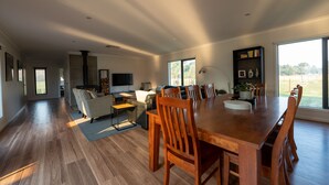 A spacious living area with a large wooden dining table, comfortable seating, a fireplace, and a view of the outdoors.