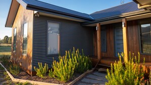 A modern house with a sloped roof, large windows, and a wooden deck.