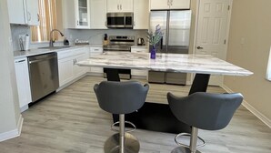 Een moderne keuken met witte kasten, roestvrijstalen apparatuur en een marmeren aanrecht.