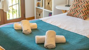 Cama bem arrumada com manta verde-água e toalhas dobradas.