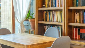 Uma mesa de madeira com cadeiras em um quarto com estantes.