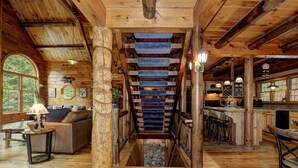 Un intérieur en bois avec un escalier, un espace de vie comprenant un canapé et un coin cuisine.