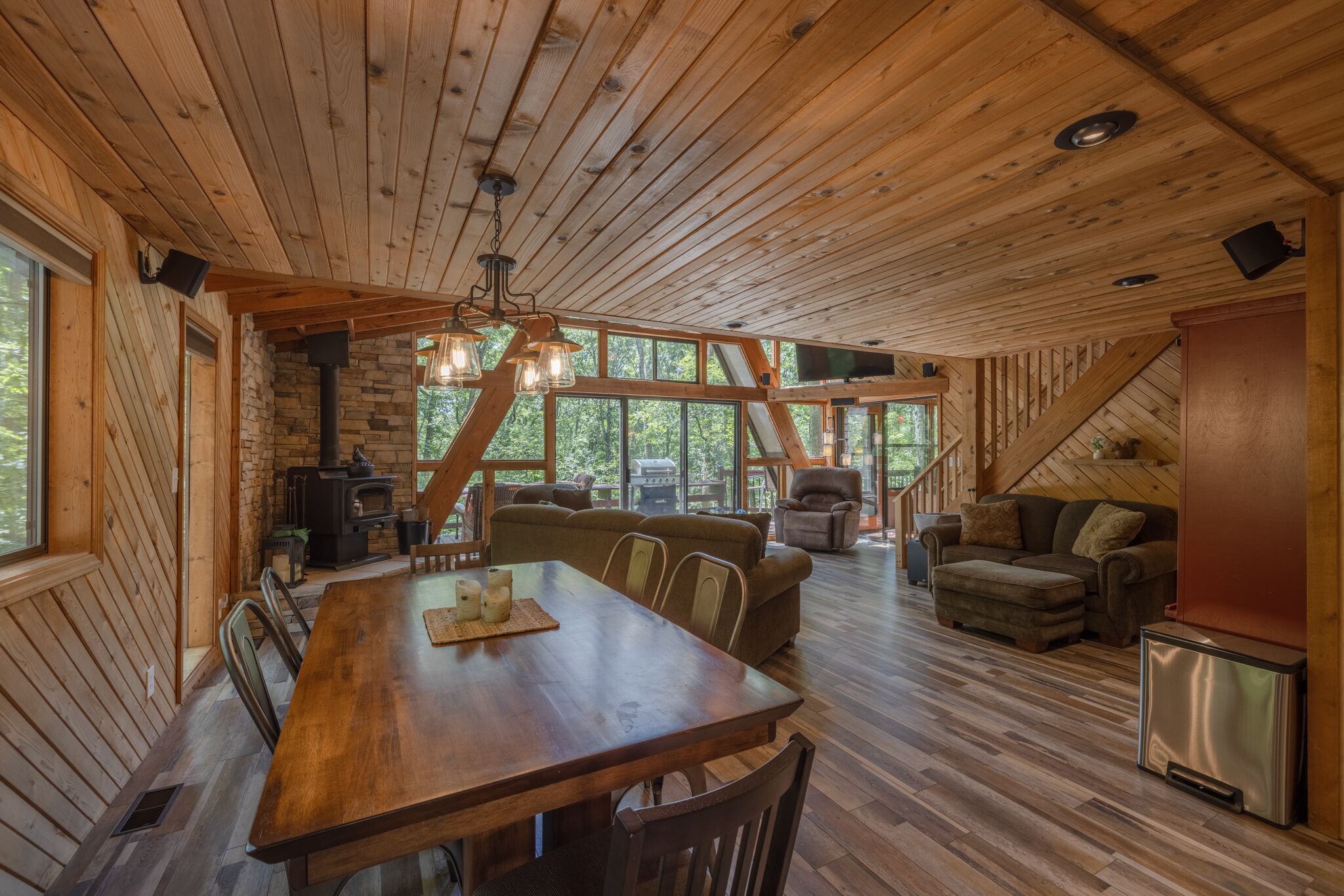 Une cabane en bois spacieuse, dotée d’un coin repas, de canapés et d’une cheminée.