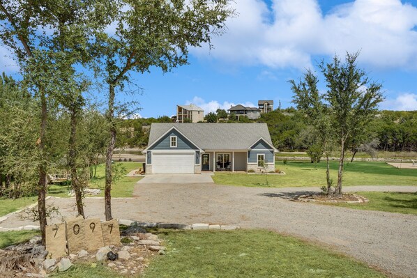 A single-story house with a garage, surrounded by a well-maintained lawn and trees.