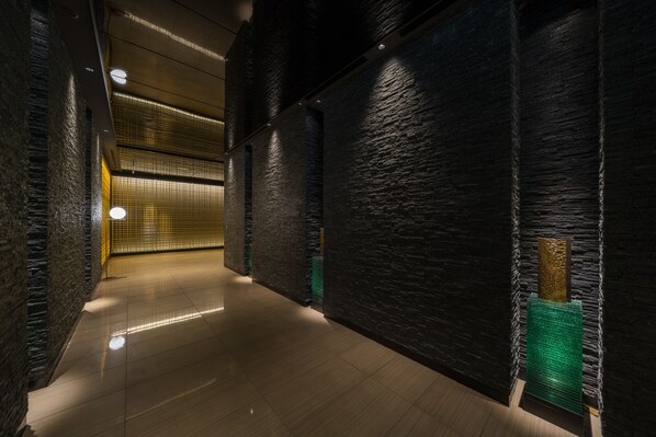 A corridor with dark brick walls and a tiled floor. - KOKO HOTEL Premier Kumamoto (Kumamoto)