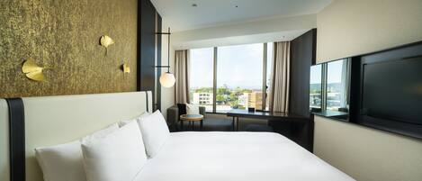 Une chambre d’hôtel avec un grand lit, une télévision, un bureau et une vue sur la ville.