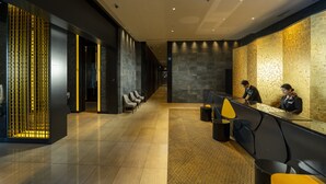 A modern reception area with a long reception desk, several seating areas, and a decorative wall with a geometric pattern. - KOKO HOTEL Premier Kumamoto (Kumamoto)