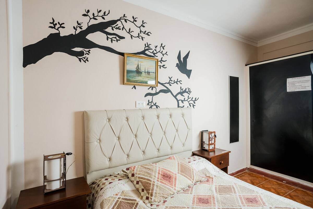 Une chambre à coucher comprenant un lit, une table de chevet, un cadre photo fixé au mur et un tableau noir.