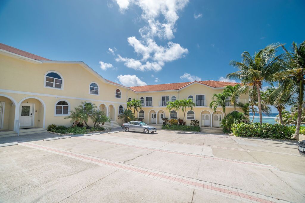 A hotel with a courtyard, palm trees, and a car parked in front.