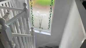 Una escala amb barana blanca i graons amb moqueta que condueix a un aterri.