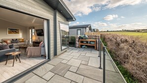Ett modernt hus med en uteplats som har en soffa, ett soffbord och utomhusmöbler.