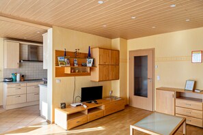 A modern kitchen with wooden cabinets, a built-in stove, and a dining area with a glass table.