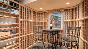 Une cave à vin avec des étagères en bois, une table et des chaises.