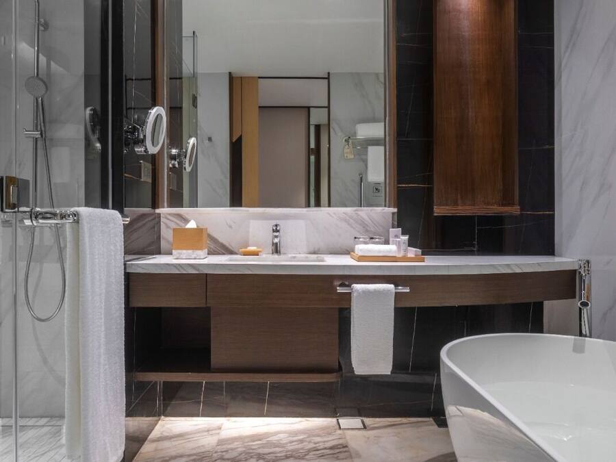 A modern bathroom with a glass shower enclosure, a freestanding bathtub, and a vanity with a mirror.