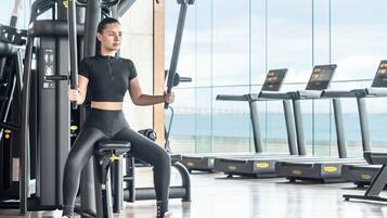 A gym with exercise equipment, treadmills, and a view of the sky.