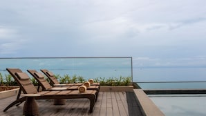 Un área de lounge en la azotea con sillones de mimbre y una piscina.