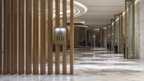 Un pasillo moderno de hotel con suelo de mármol, paneles verticales dorados y un letrero que dice 'fili'.