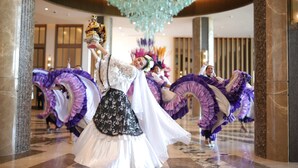 Un salón de baile con bailarines en trajes tradicionales, suelos de mármol y un techo decorativo.