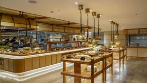 A modern restaurant with a central bar area, wooden tables, and hanging pendant lights.