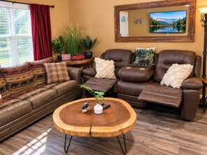 A living room with a brown leather sofa, a wooden coffee table, and a television on the wall.