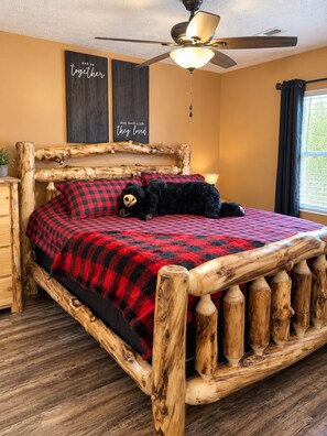 A bed with a wooden frame, a red and black checkered blanket, and two pillows. - WOW 🤩 3BR Cabin just 2 miles to Dollywood + Arcades! (Sevierville)