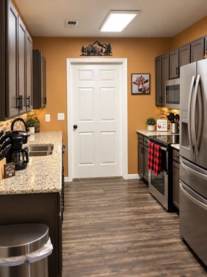 A kitchen with dark cabinets, a stainless steel refrigerator, a microwave, and a double oven. - WOW 🤩 3BR Cabin just 2 miles to Dollywood + Arcades! (Sevierville)