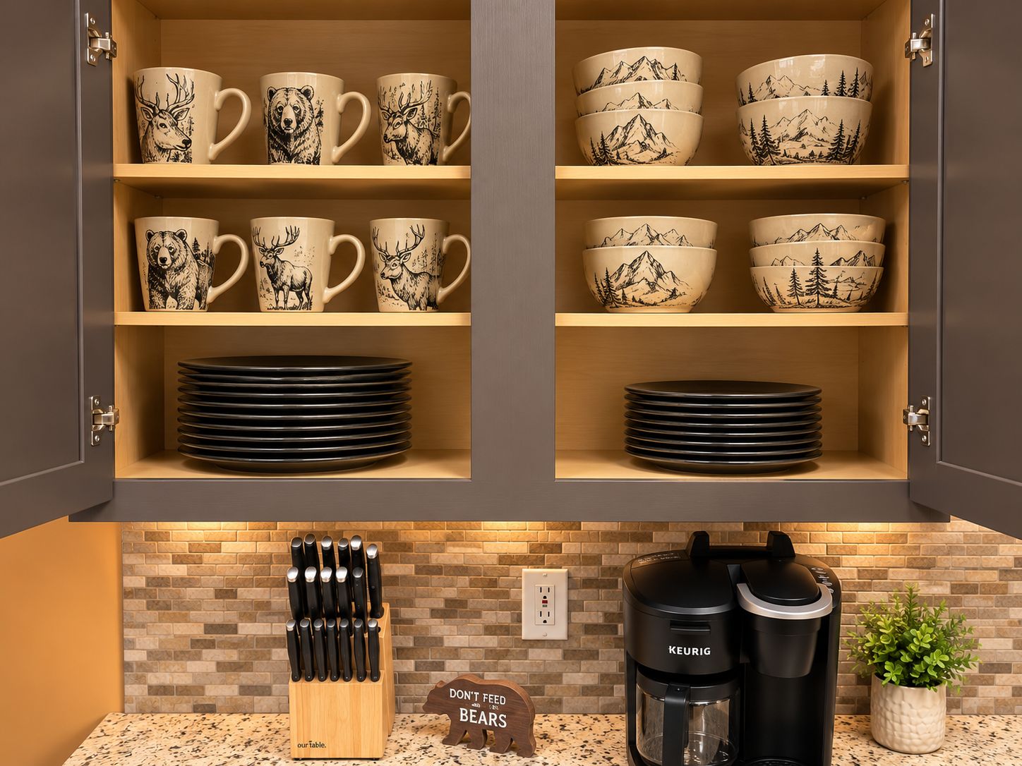 A kitchen cabinet with mugs and bowls featuring wildlife prints, a knife block, and a coffee maker.