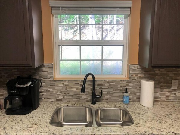 A kitchen with a window, two stainless steel sinks, a coffee maker, and a soap dispenser. - WOW 🤩 3BR Cabin just 2 miles to Dollywood + Arcades! (Sevierville)