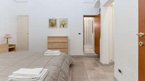 Une chambre à coucher avec un lit, une tête de lit en bois, une table de chevet, une lampe et deux tableaux encadrés accrochés au mur.