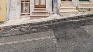 Un immeuble de deux étages doté d’un balcon, d’une porte verte et d’un escalier menant à l’entrée.